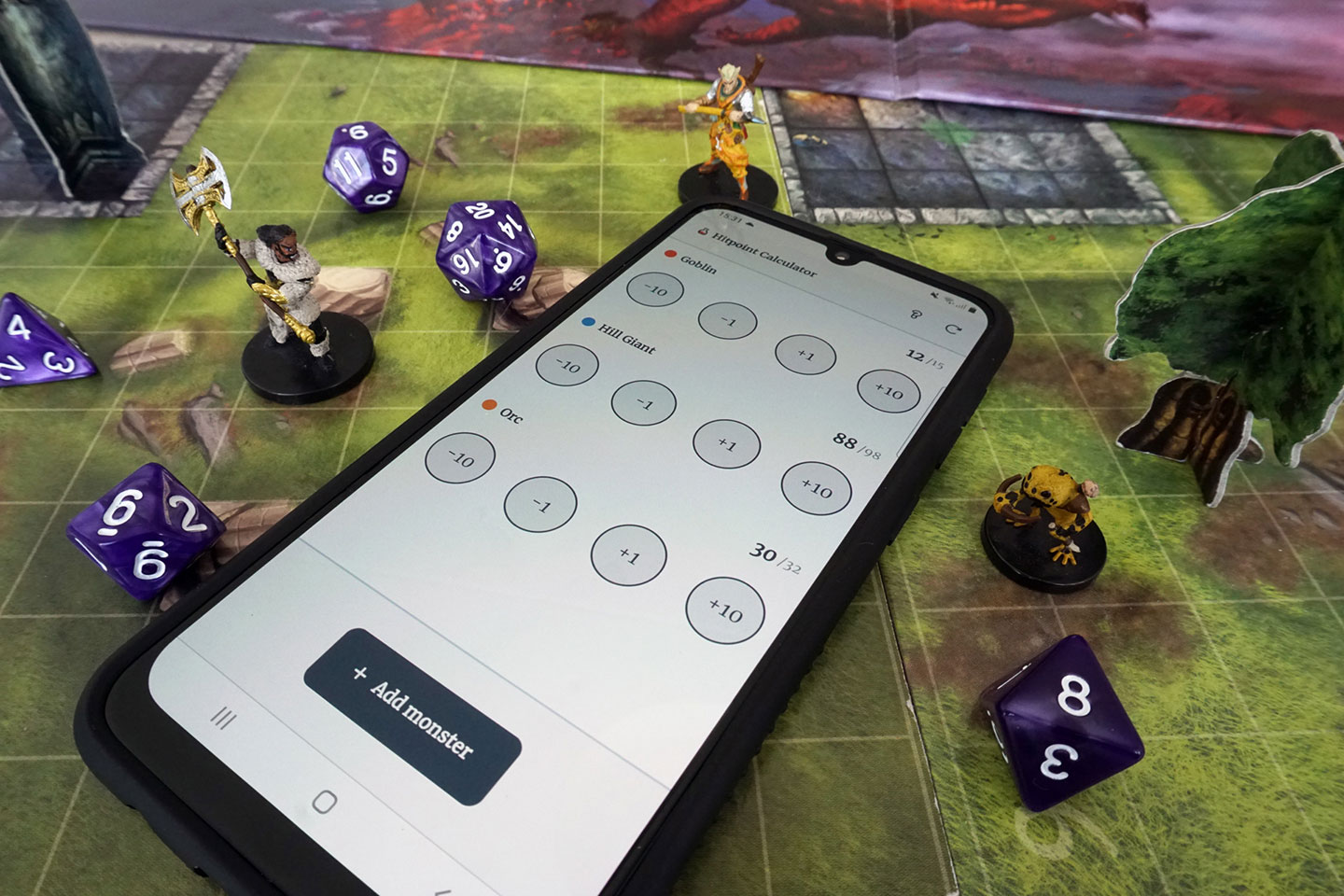 Phone with mockup of hitpoint calculator app open in between of d and d miniatures