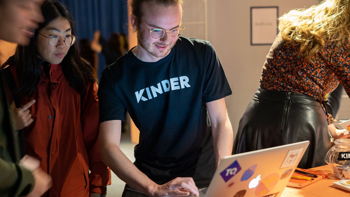Koen Hoogendoorn wearing a Kinder shirt at a reception desk helping people