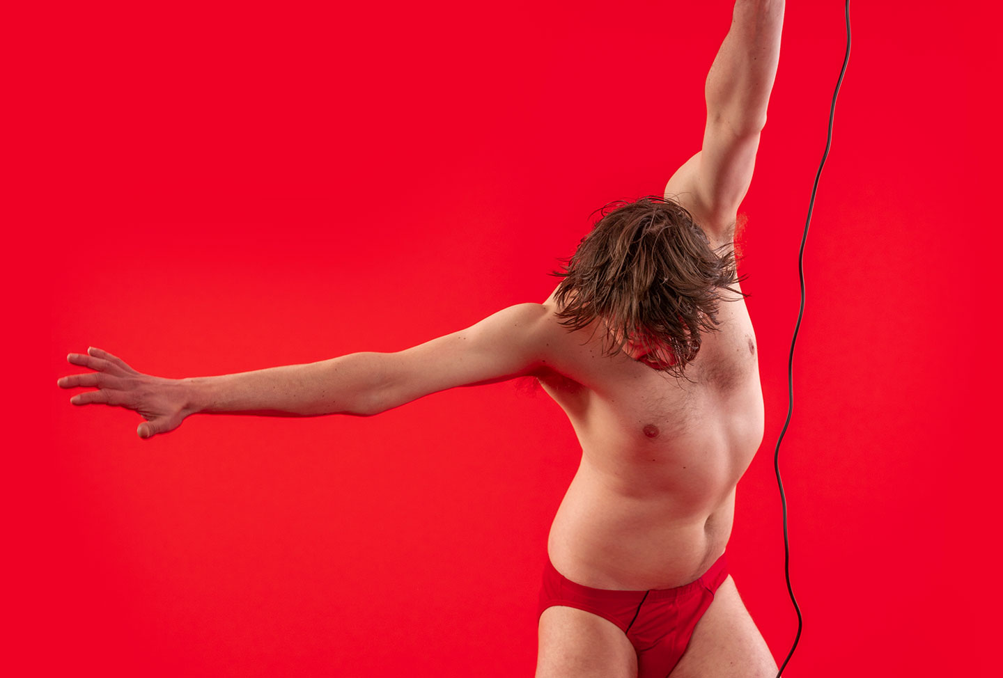 Photo of a Stefano Keizers in his underwear in front of a red background